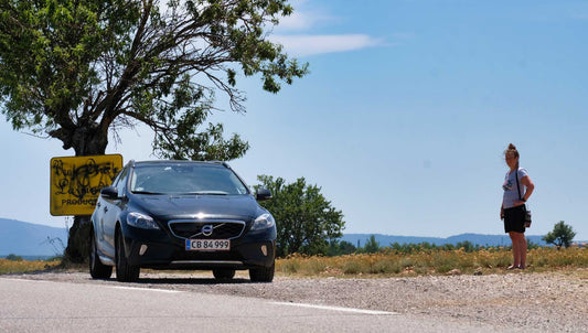 Volvo og kvinde i vejsiden på en steghed sommerdag